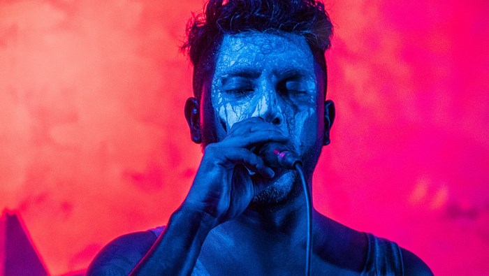 Man with face paint singing into a microphone