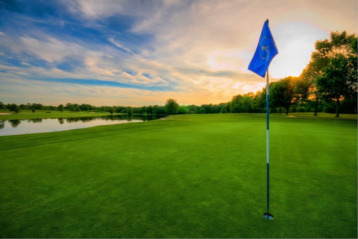 Golf course with flag and lake at sunset
