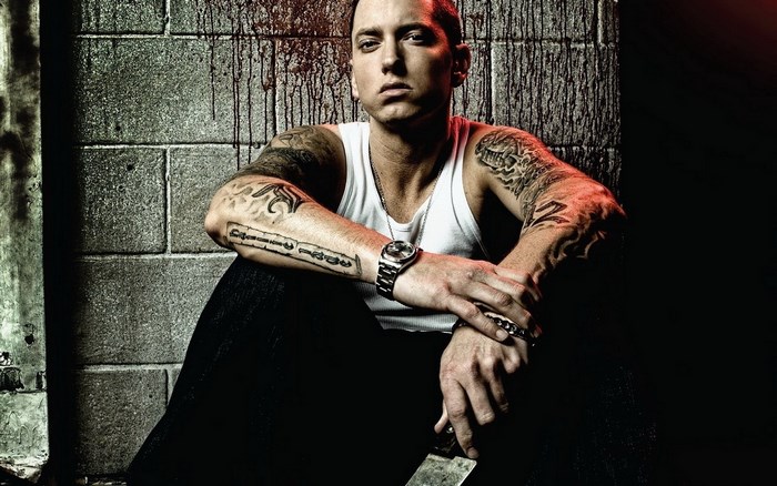 Eminem sitting against a brick wall