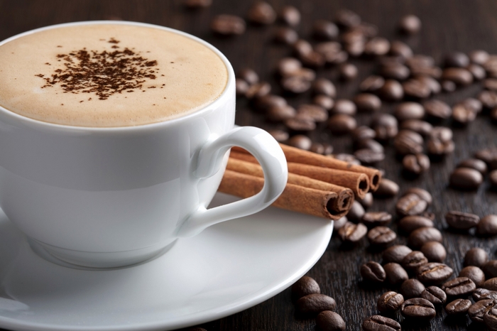 Cup of coffee with cinnamon sticks and coffee beans