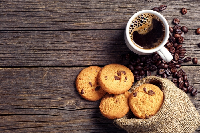 Coffee cup with cookies and coffee beans on a wooden table