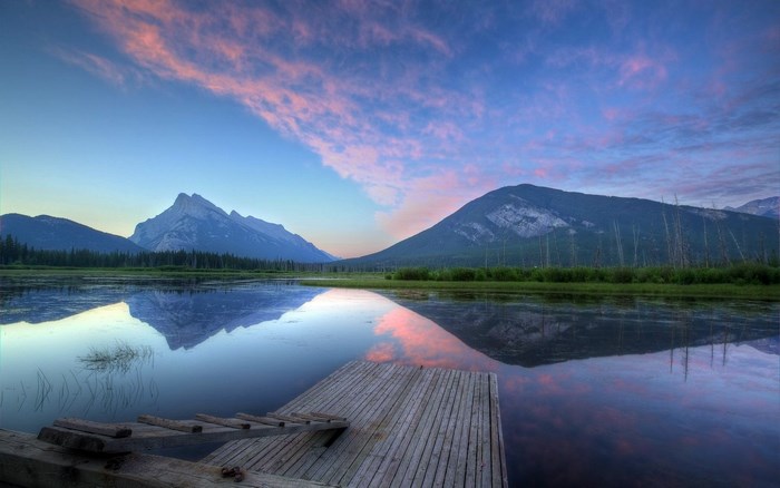 Mountain reflection on lake at sunrise with wooden dock