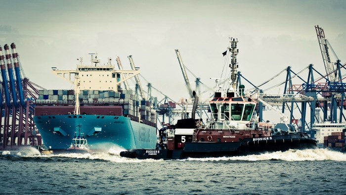 Container ship and tugboat in a busy port