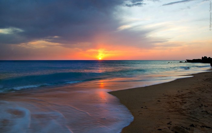 Sunset over the ocean with waves on the beach