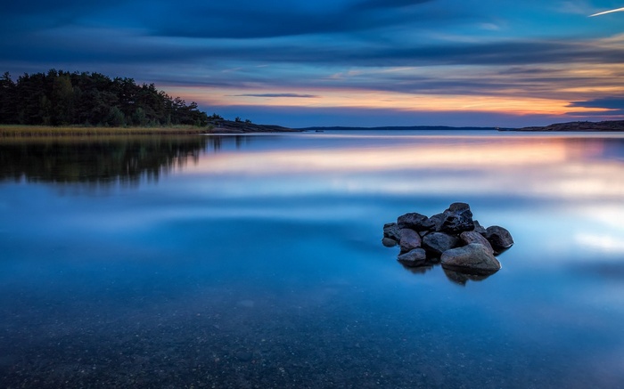Calm lake at sunset with rocks