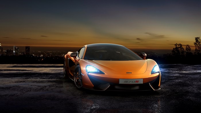 Orange McLaren 570S parked at dusk with city skyline