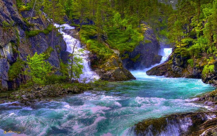 Turquoise river flowing through a rocky forest with waterfalls