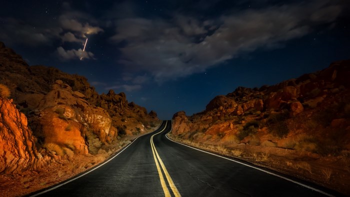 Road through desert mountains at night