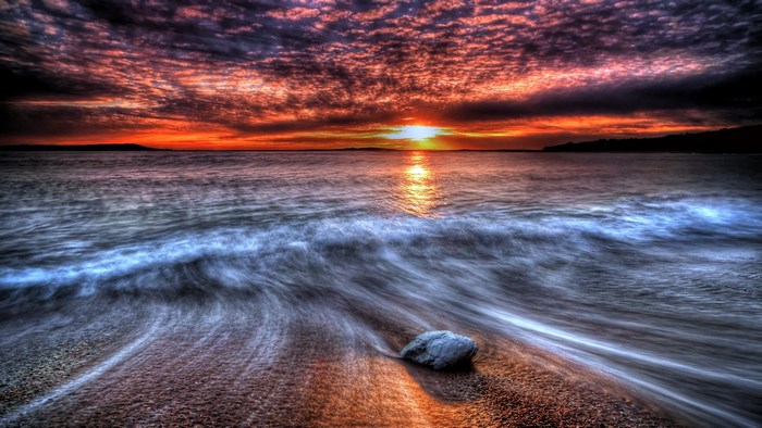 Sunset over the ocean with waves on the beach