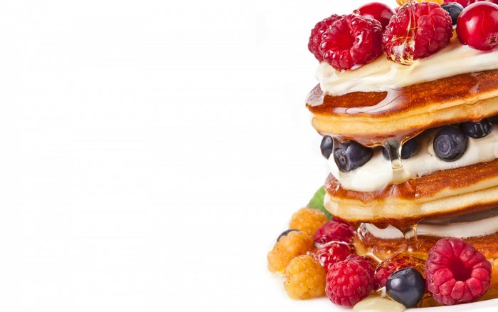 Stack of pancakes with berries and cream