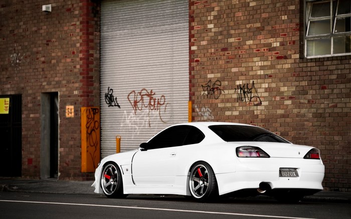 White Nissan Silvia S15 parked by brick building