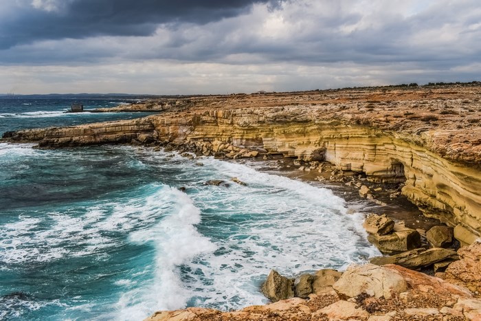 Rocky coastline with crashing waves under a cloudy sky