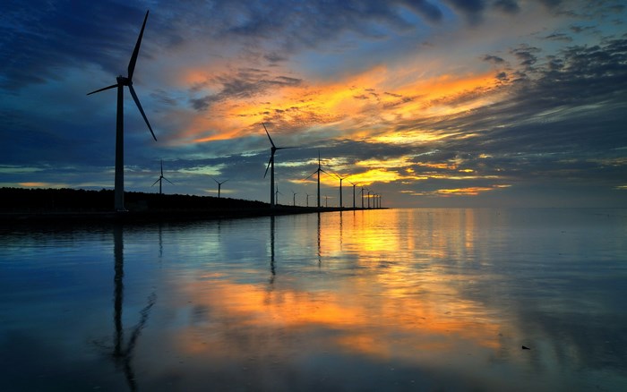 Wind turbines at sunset over water