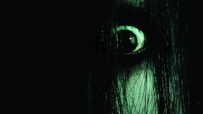Close-up of a pale eye with long black hair