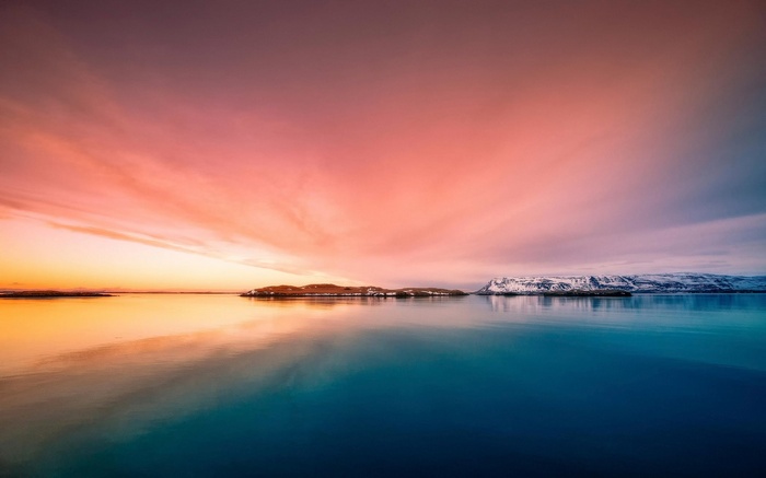 Sunset over a calm body of water with islands and mountains