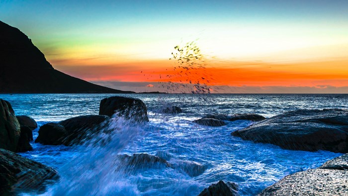 Ocean waves crashing on rocks at sunset