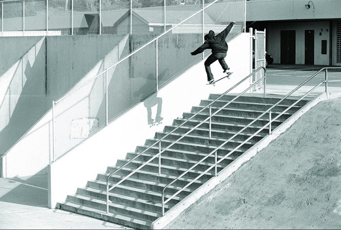 Skateboarder jumps down a long set of stairs