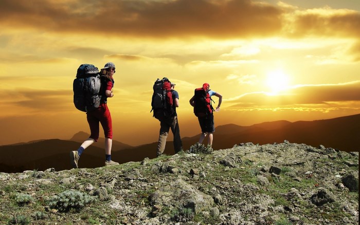 Three Hikers Trekking at Sunset on Rocky Terrain