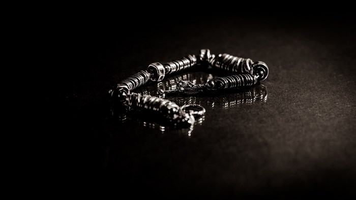 Silver bracelet with coiled links on a dark surface