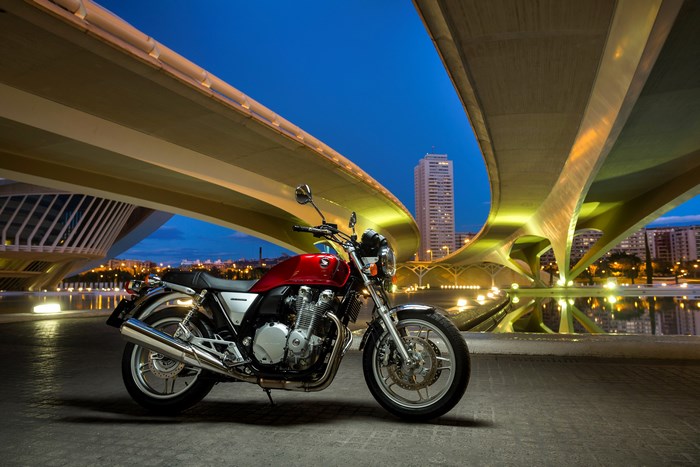Red Honda CB1100 motorcycle under a modern bridge at night