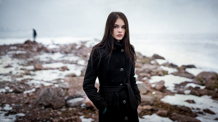 Young Woman in Black Coat on Rocky Beach