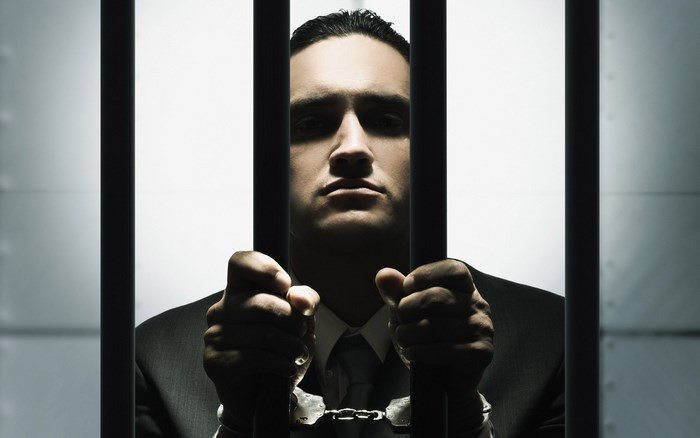 Man in handcuffs behind prison bars