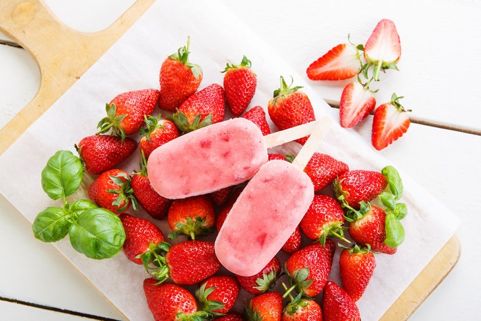 Strawberry popsicles and fresh strawberries on a wooden board