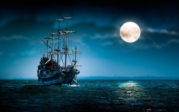 Pirate ship sailing on the ocean under the full moon