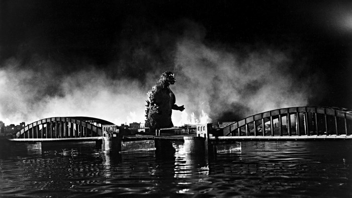 Godzilla attacking a city with bridges and fire