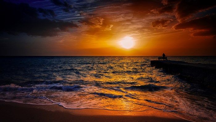 Sunset over Calm Ocean with Pier Silhouette