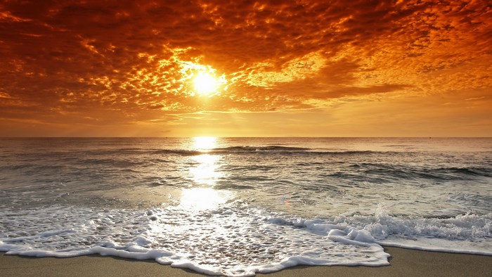Sunset over the ocean with waves on the beach