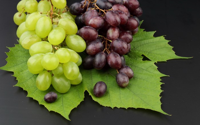 Green and red grapes on a black background