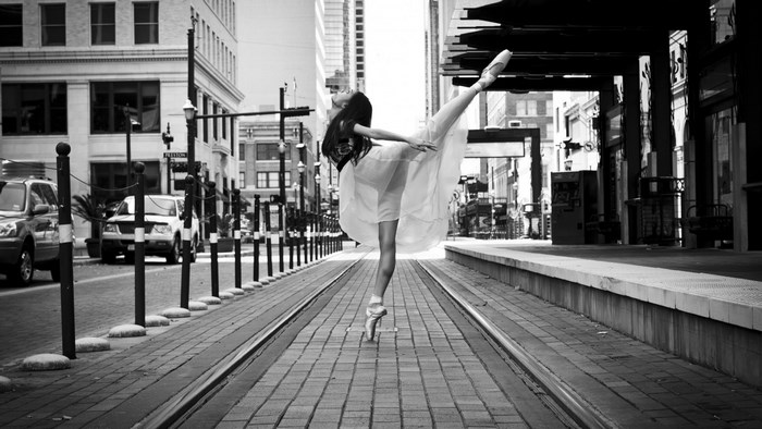 Ballerina dancing on city street with tram tracks