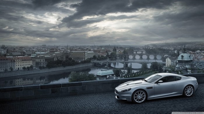 Aston Martin DBS on a cobblestone street overlooking Prague