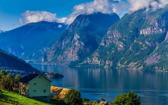 Yellow house by a fjord with mountains