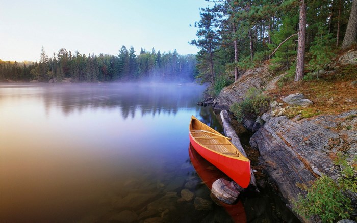 Red canoe on a misty lake at sunrise