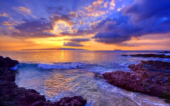 Sunset over the ocean with rocky shore