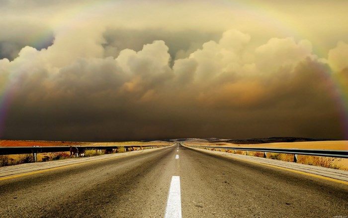 Road with rainbow and stormy clouds