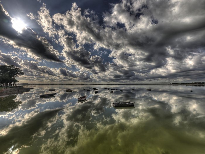 Boats on a reflective lake under a dramatic sky