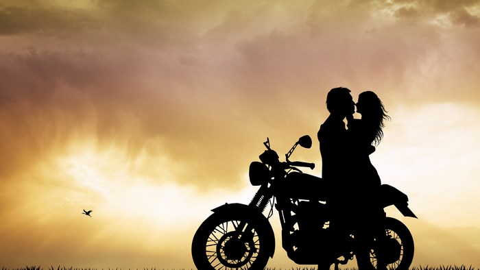 Couple kissing on a motorcycle at sunset