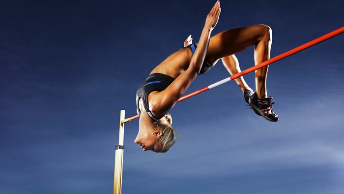 Woman high jumping over bar