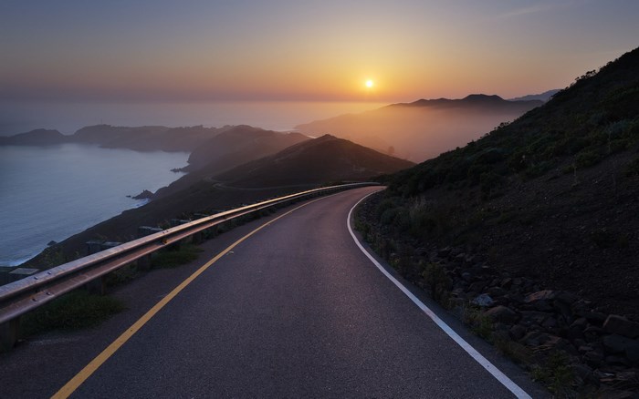 Coastal road at sunset with ocean and mountains