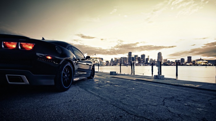 Black Sports Car on Waterfront with City Skyline