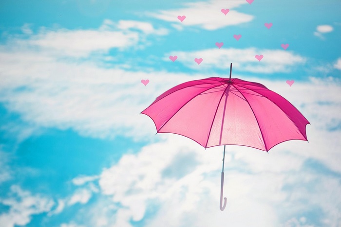 Pink umbrella floating in the sky with hearts