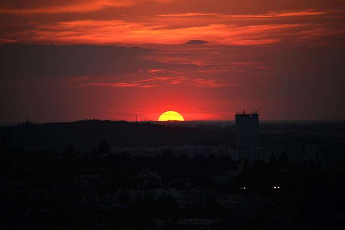 Sunset over a city skyline with a tall building