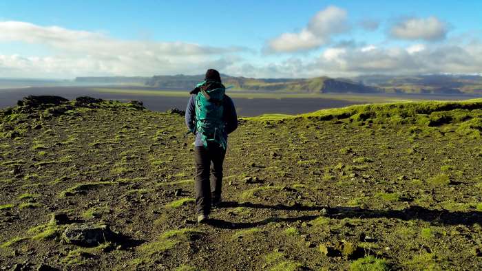 Person with backpack hiking on a mossy hill