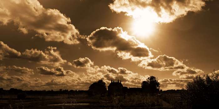 Sepia toned landscape with dramatic clouds and sun