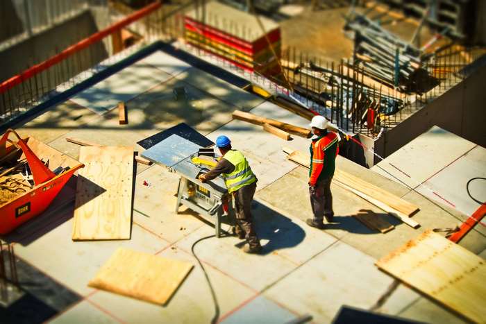 Construction workers operating a table saw on a building site