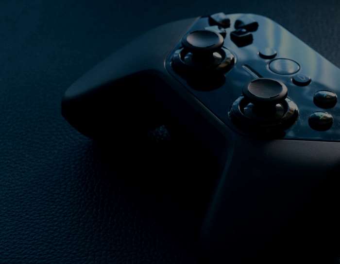 Close up of a black gaming controller on a dark surface