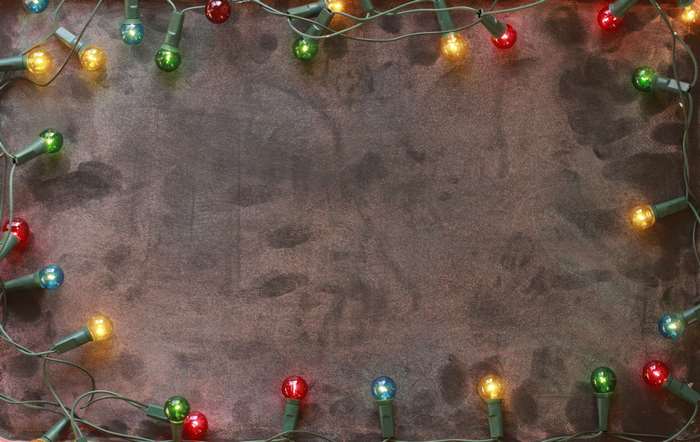 Colorful Christmas lights frame a dark textured surface